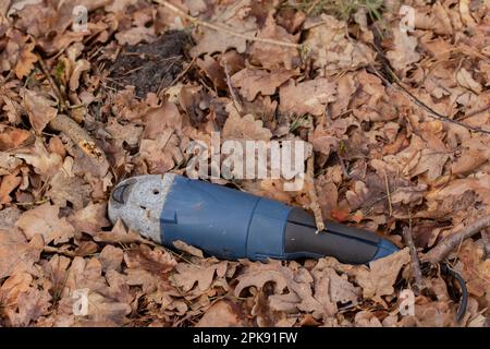 Pollution, illegally discarded angle grinder in a forest Stock Photo