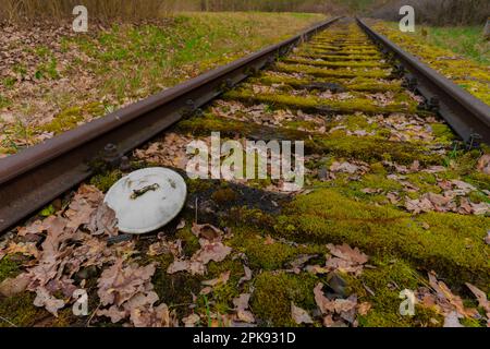 old railway track near Berlin in Germany, old Emallie cooking pot lid lies in the track bed Stock Photo
