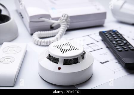Smoke detector, remote controls and building plan on white background, closeup. Home security system Stock Photo