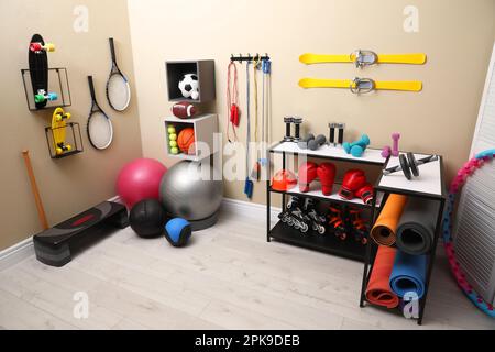 Many different sports equipment in room with beige walls Stock Photo