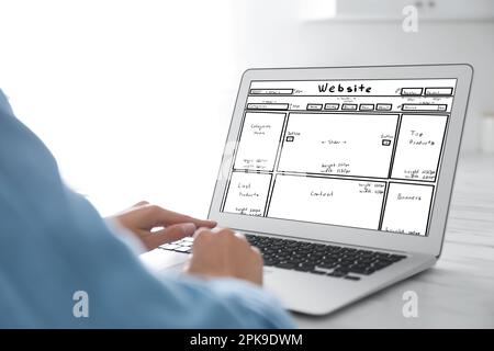 Designer creating website on laptop at white table, closeup Stock Photo