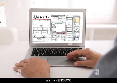 Designer creating website on laptop at white table, closeup Stock Photo