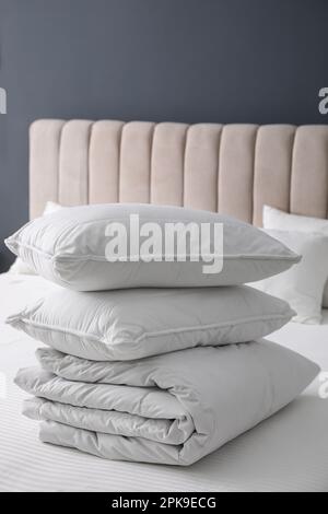 Soft folded blanket and pillows on bed indoors Stock Photo