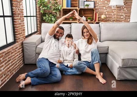 Family of three doing house shape with arms scared and amazed with open mouth for surprise, disbelief face Stock Photo
