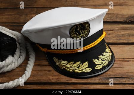 Peaked cap and rope with binoculars on wooden background Stock Photo