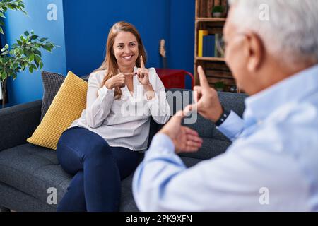 Middle age man and woman couple using deaf sign language at home Stock Photo
