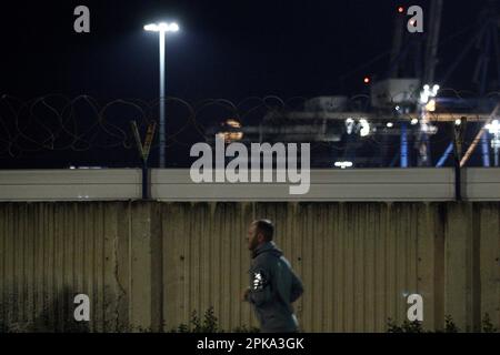 Limassol, Cyprus. 06th Apr, 2023. A man is seen running while the Pink Full Moon is rising above the port of Limassol on Apr. 6, 2023. The pink moon gets its name from a hot pink wildflower, Phlox subulata, that grows in a thick mat of vibrant foliage, commonly referred to as creeping phlox, moss phlox or moss pink. (Photo Kostas Pikoulas/SIPA USA). Credit: Sipa USA/Alamy Live News Stock Photo