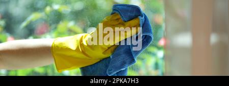 Woman cleaning window using detergent and rags Stock Photo
