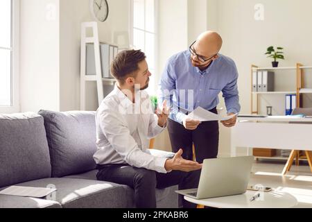 Two young business men at work in office talking and having discussion. Stock Photo