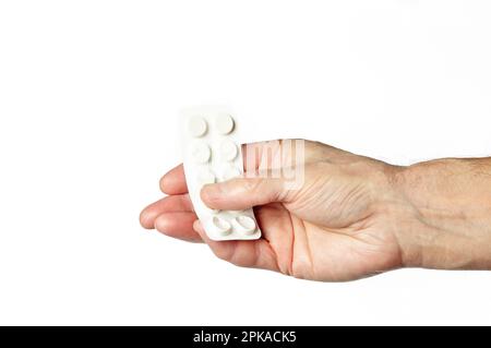 Men's hand holding white pills in common tablets shape isolated on white background. Hand with pills, closeup Stock Photo