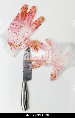 Red discolored pair of disposable glove with knife on a white surface Stock Photo