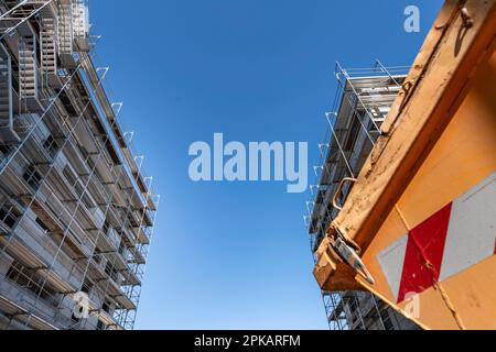 Unusual perspective with cut of an oragen waste container on a construction site with two buildings under construction in the background Stock Photo