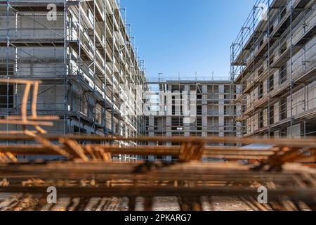 Rusty steel probation lies stacked on the ground at a large construction site with multi-story buildings in the shell in the background Stock Photo