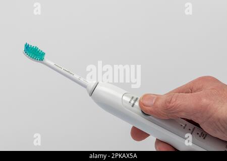 Man hand holding Philips Sonicare electric toothbrush type HX 6730, sonic toothbrush, white background, Stock Photo