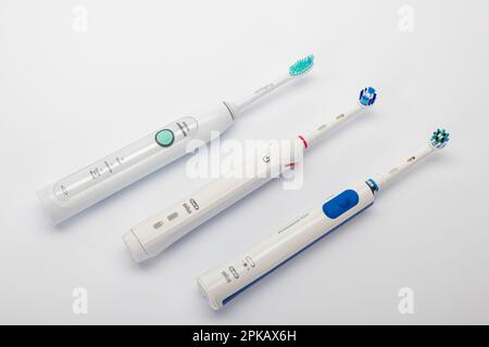 Three different electric toothbrushes, Braun Oral-B, Philips Sonicare, white background, Stock Photo