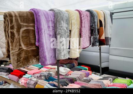 Stacked assortment of colorful towels and blankets at farmer market, Nikiti, Sithonia, Greece. Selective focus. Stock Photo
