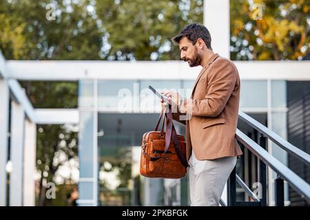 Portrait of businessman using a digital tablet while standing in front of modern building. Stock Photo
