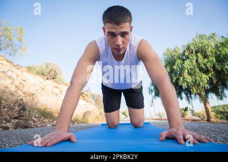 A young athlete during a workout with a mat in an open-air park, health lifestyle Stock Photo