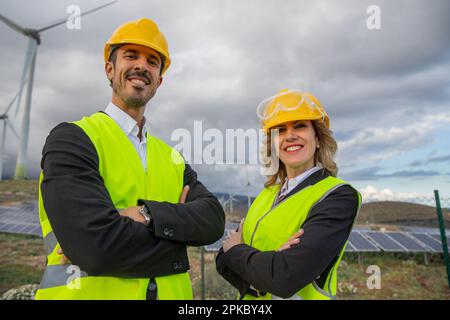 Two smiling engineers with folded arms at a solar power plant. Stock Photo