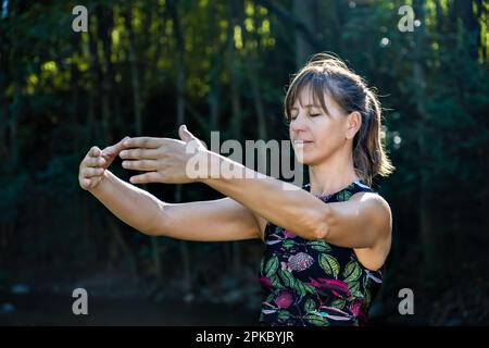Qigong Female Master Practicing Chinese Martial Arts in Nature. Sunlight illuminates the scene Stock Photo