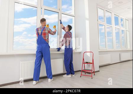 Workers using suction lifters during plastic window installation indoors Stock Photo