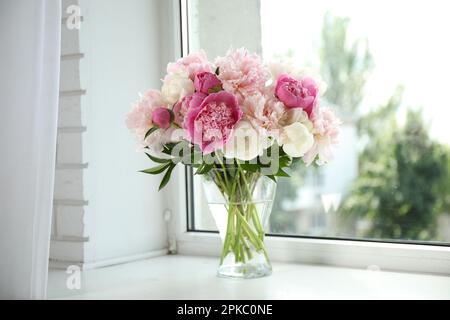 Beautiful peony bouquet in vase on windowsill indoors Stock Photo