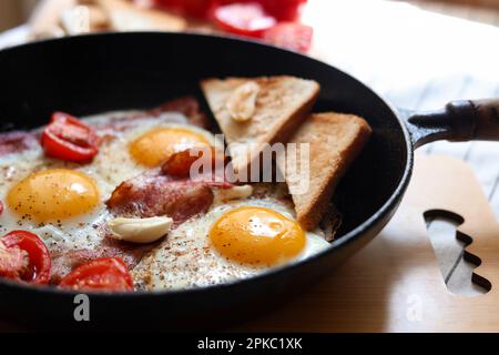 Delicious fried eggs with bacon and tomatoes in pan, closeup Stock Photo