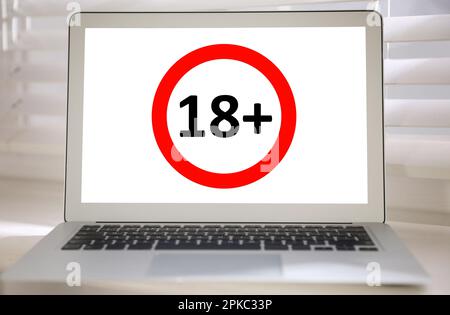 Laptop screen with age limit sign 18+ years on window sill Stock Photo