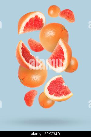 Tasty ripe grapefruits falling on light background Stock Photo