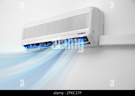 Modern conditioner and illustration of cool air flow on white wall indoors Stock Photo