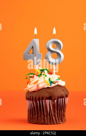 Birthday cake with candle number 48 - Orange background Stock Photo - Alamy