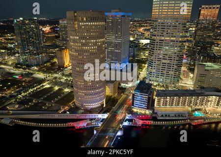 Aerial view of downtown district of Tampa city in Florida, USA. Brightly illuminated high skyscraper buildings, pedestrian riverwalk and moving Stock Photo