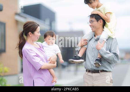 Baby being carried by mother and girl being carried by father Stock Photo