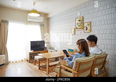 Woman sitting on sofa in living room operating tablet device Stock Photo