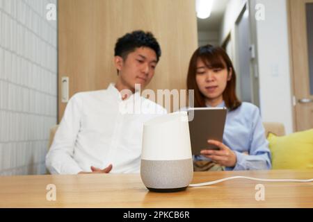 A man and a woman relaxing in the living room with AI speakers on the table Stock Photo