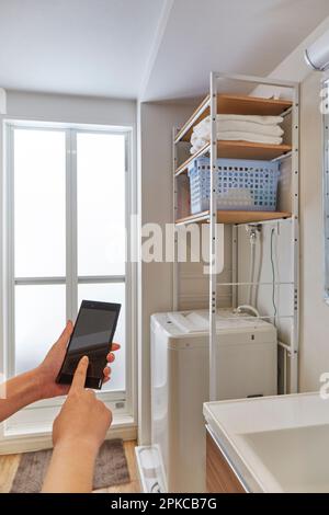 Woman operating washing machine at home Stock Photo - Alamy