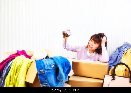 Woman with purse and room cluttered with clothes and bags coming out of boxes Stock Photo