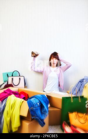 Woman with purse and room cluttered with clothes, bags, etc. coming out of box Stock Photo