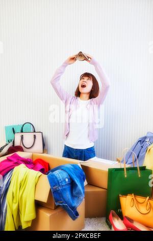 Woman with purse and room cluttered with clothes, bag, etc. coming out of box Stock Photo