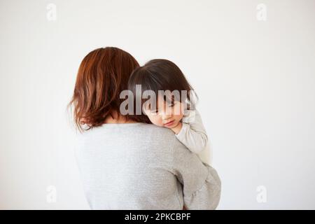 Baby lying face down in mother's arms Stock Photo