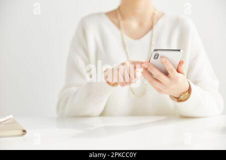 Woman sitting in front of a desk operating a smartphone Stock Photo