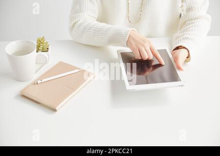 Woman operating a tablet sitting at a desk Stock Photo
