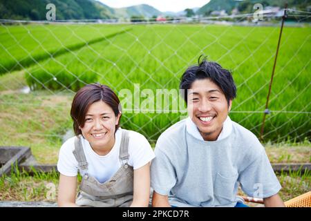 Smiling men and women in front of a paddy field Stock Photo