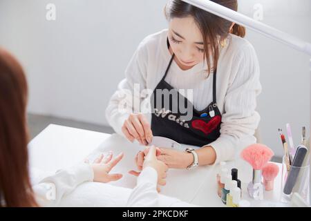 Manicurist applying manicure to a customer's nails Stock Photo