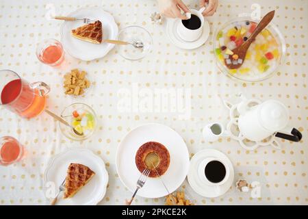 Woman drinking coffee with a table full of sweets Stock Photo
