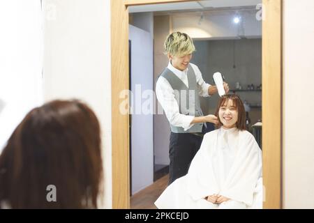 A beautician drying a client's hair Stock Photo