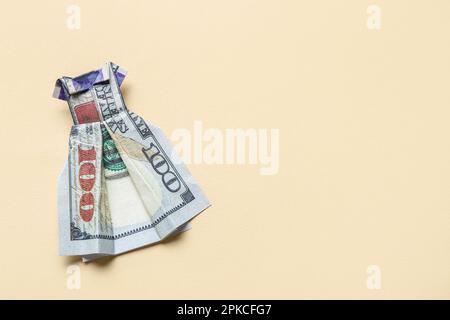 Origami dress made of dollar banknotes on beige background Stock Photo