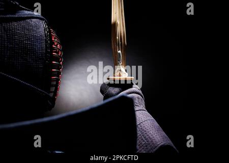 A man wearing a kendo-gi holding a shinai in front of his face Stock Photo