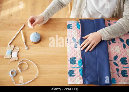 Woman's hand pointing a needle to a cloth on the table Stock Photo