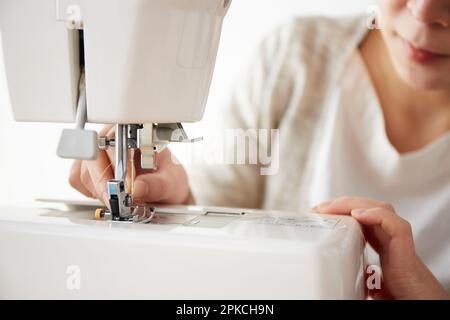 A woman threading a needle on a sewing machine Stock Photo